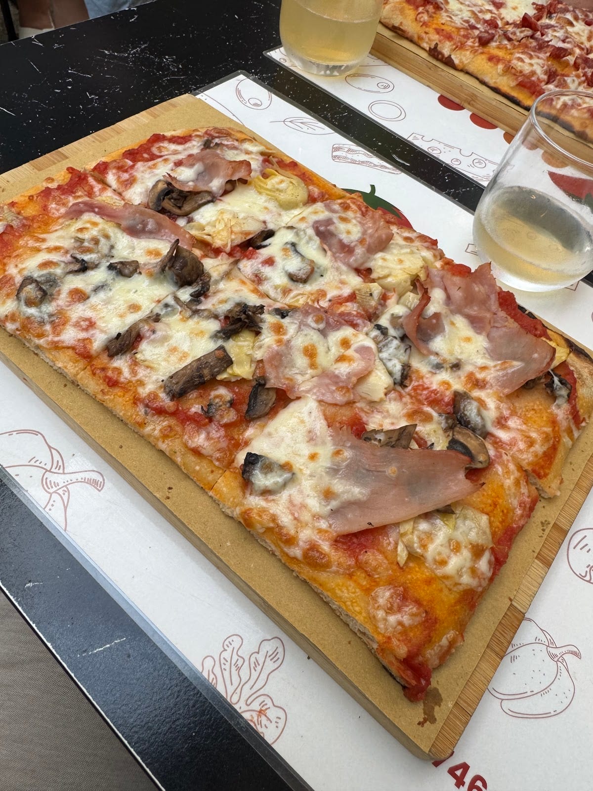 Pizza rettangolare con prosciutto, funghi e carciofi